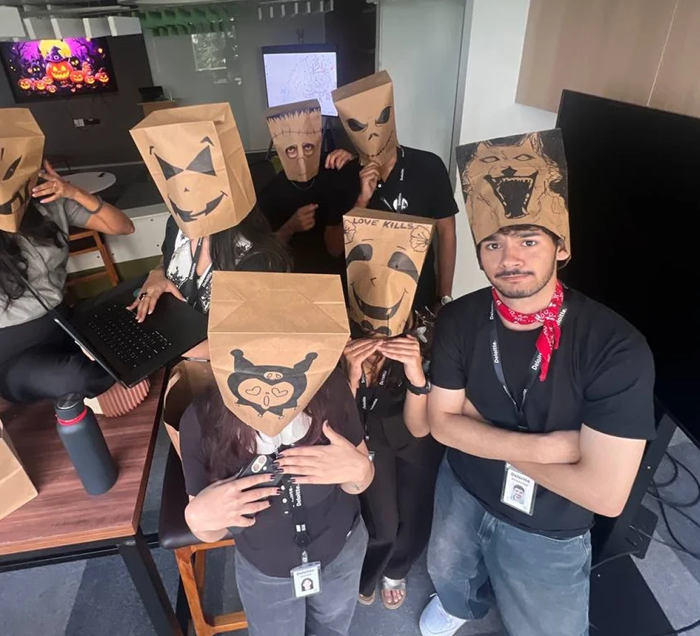 Hemant with teammates, all wearing hand-drawn paper bag masks